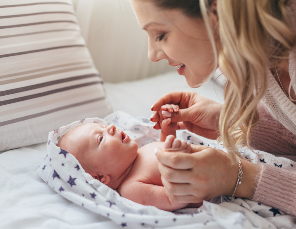Mother gently talking and holding newborn baby encouraging communication and emotional brain development