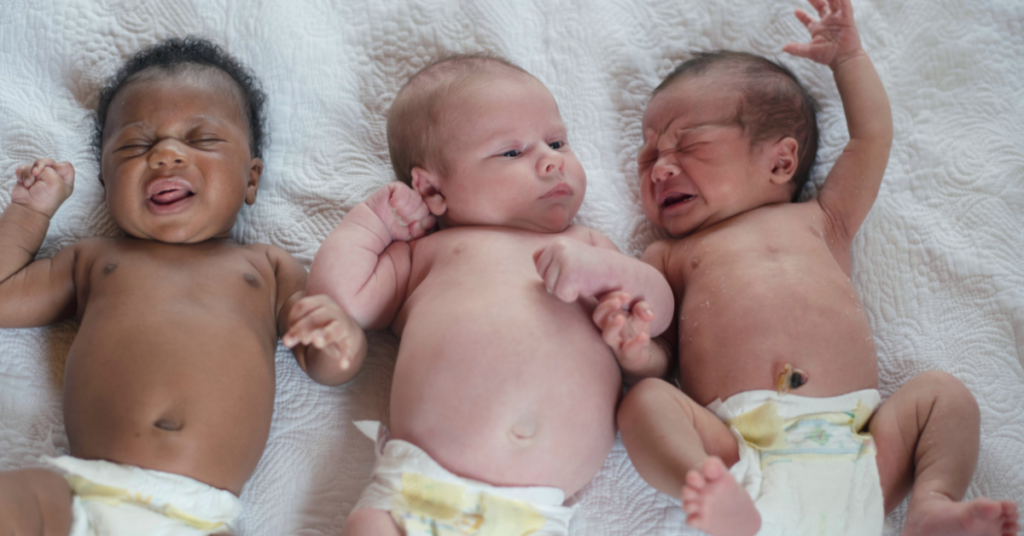 Three newborn babies lying side by side representing the natural variety in infant developmental milestones.