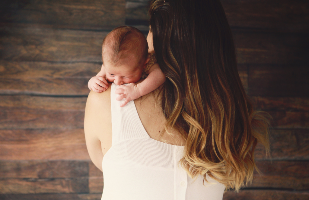  Mother burping newborn baby over her shoulder using the classic upright burping technique