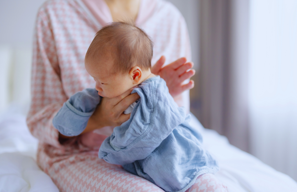 Newborn baby in lap burping position to help relieve gas and air bubbles after feeding