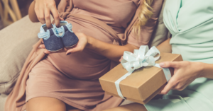 pregnant-woman-holding-baby-shoes-receiving-gift-at-baby-shower